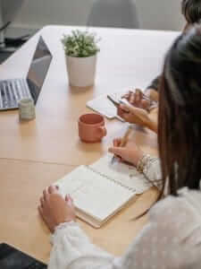 femme qui écrit sur un carnet vue de dos durant une réunion