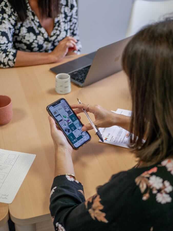 réunion d'équipe à l'agence de communication com' commerce, une femme regarde le feed instagram d'une page pour la gestion des réseaux sociaux