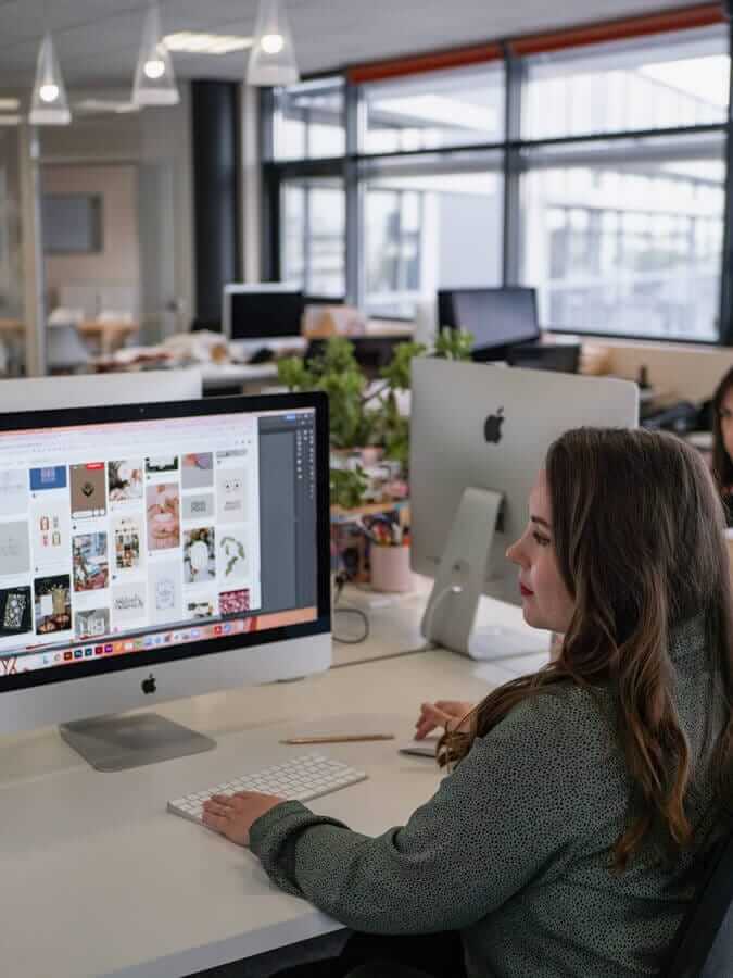 directrice artistique travaillant sur de la veille graphique derrière son ordinateur de bureau dans une agence de communication à Clermont-Ferrand