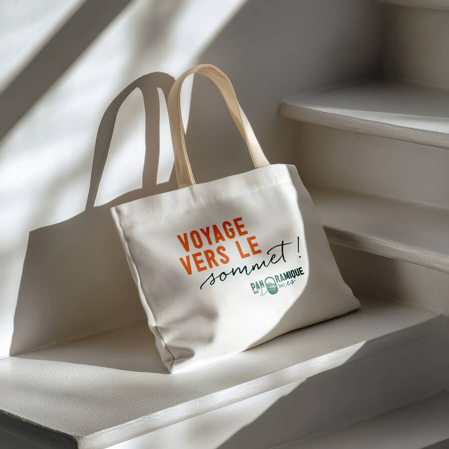 tote bag avec l'inscription "voyage vers le sommet" baseline du panoramique des domes - identité visuelle par l'agence de communication globale com' commerce