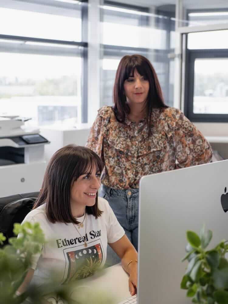 Deux femmes travaillant dans une agence de communication globale à Clermont-Ferrand, spécialisé dans la création de site internet, derrière un ordinateur de bureau
